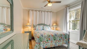 A bedroom with a bed, two bedside tables, a chair, a ceiling fan, and a window with curtains. - Wooded Couples Haven! 15 Mi to Wrightsville Beach (Wilmington)