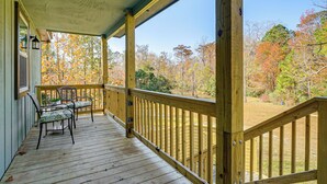 A wooden deck with chairs and a table, overlooking a forest with autumn foliage. - Wooded Couples Haven! 15 Mi to Wrightsville Beach (Wilmington)