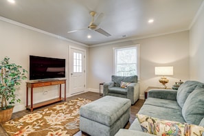 A living room with a flat-screen TV, grey sofas, a ceiling fan, a potted plant, and a floral rug. - Wooded Couples Haven! 15 Mi to Wrightsville Beach (Wilmington)