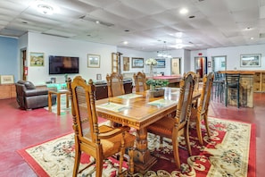A spacious room with a wooden dining table, chairs, a sofa, and a television. - 4 Mi to Mauch Chunk Lake: Spacious Apt w/ Bar! (Summit Hill)