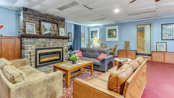 A living room with a stone fireplace, leather sofas, a coffee table, and various framed pictures on the walls.