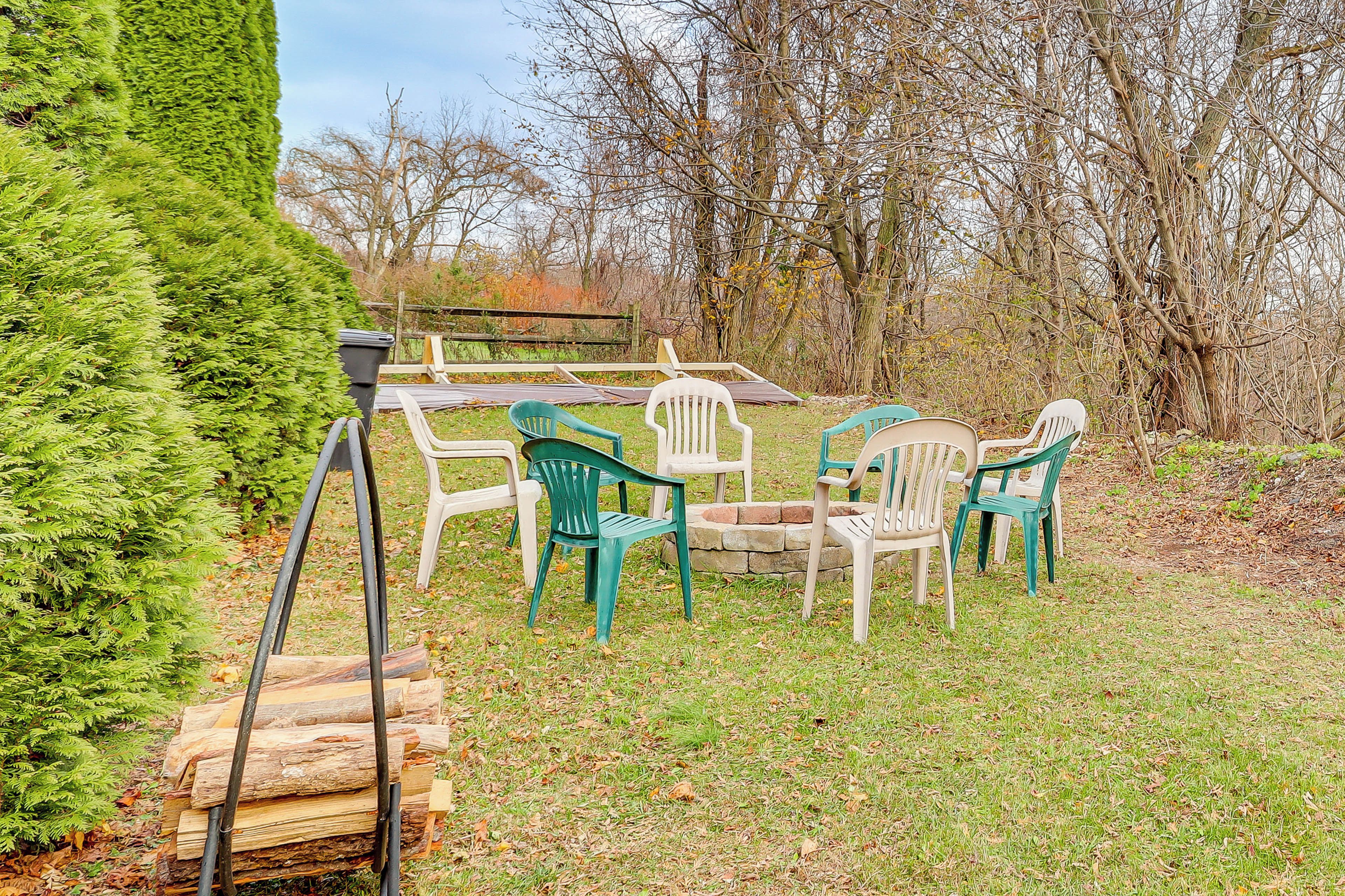 A garden with a wooden table and chairs, surrounded by trees and a hedge.