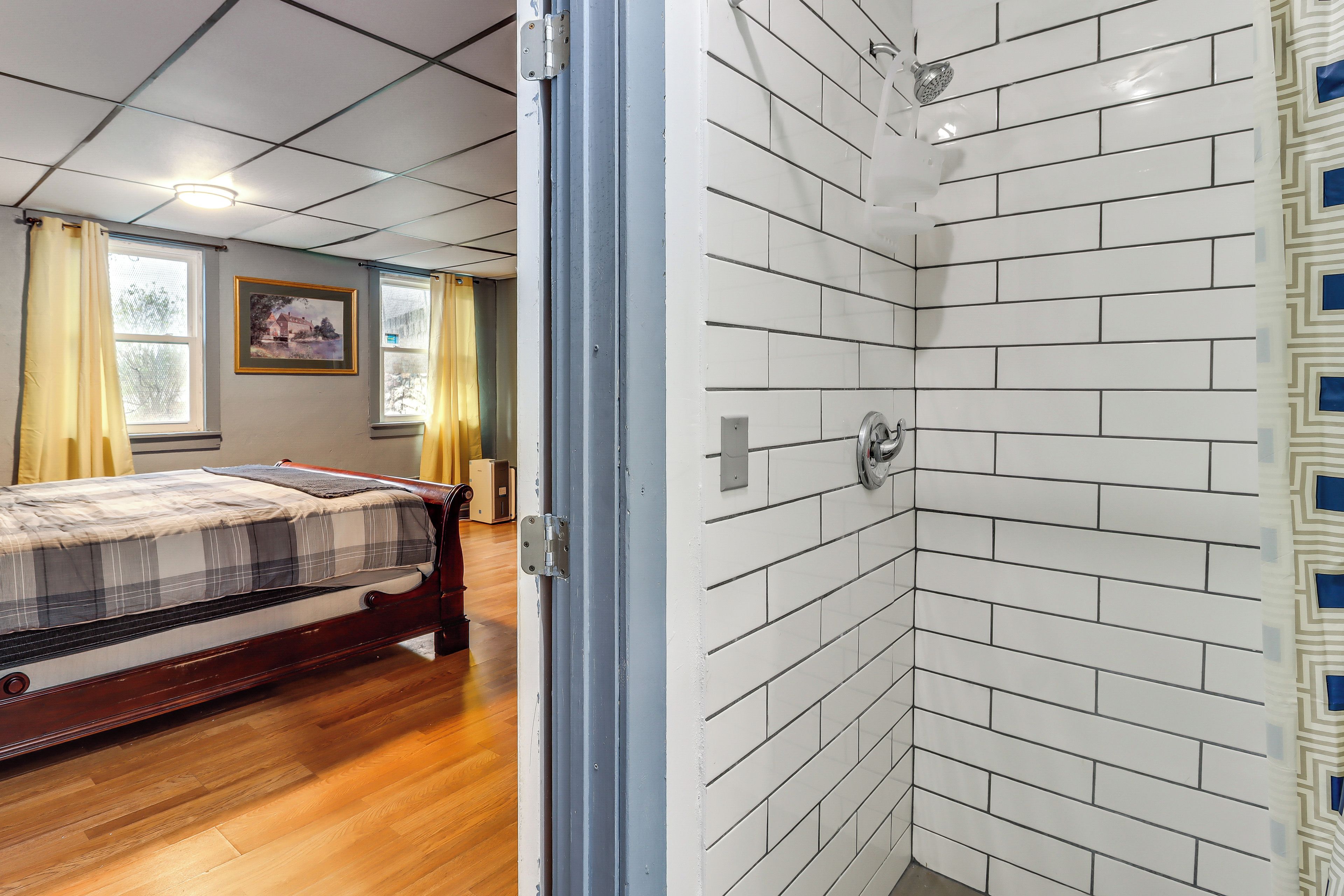 Een slaapkamer met een bed, een douche en een raam met gordijnen.