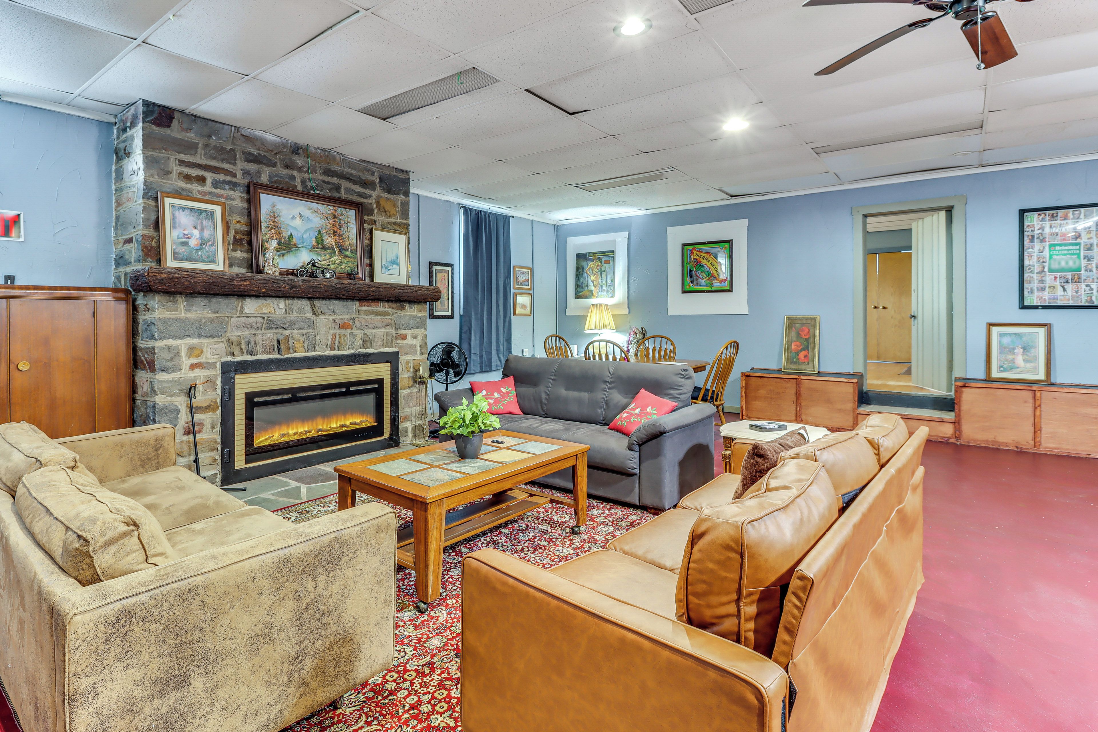 A living room with a stone fireplace, leather sofas, a coffee table, and various framed pictures on the walls.