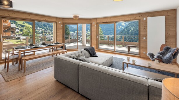 A spacious living room with a large sofa, wooden dining table, and a view of a mountainous landscape through large windows. - Thélème A201 by Avecoeur (Châtel)