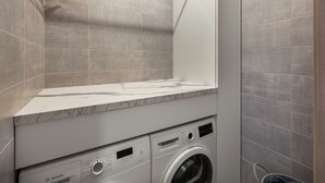 A modern laundry room with a Bosch washing machine and dryer, grey tiled walls, and a marble countertop. - Thélème A201 by Avecoeur (Châtel)
