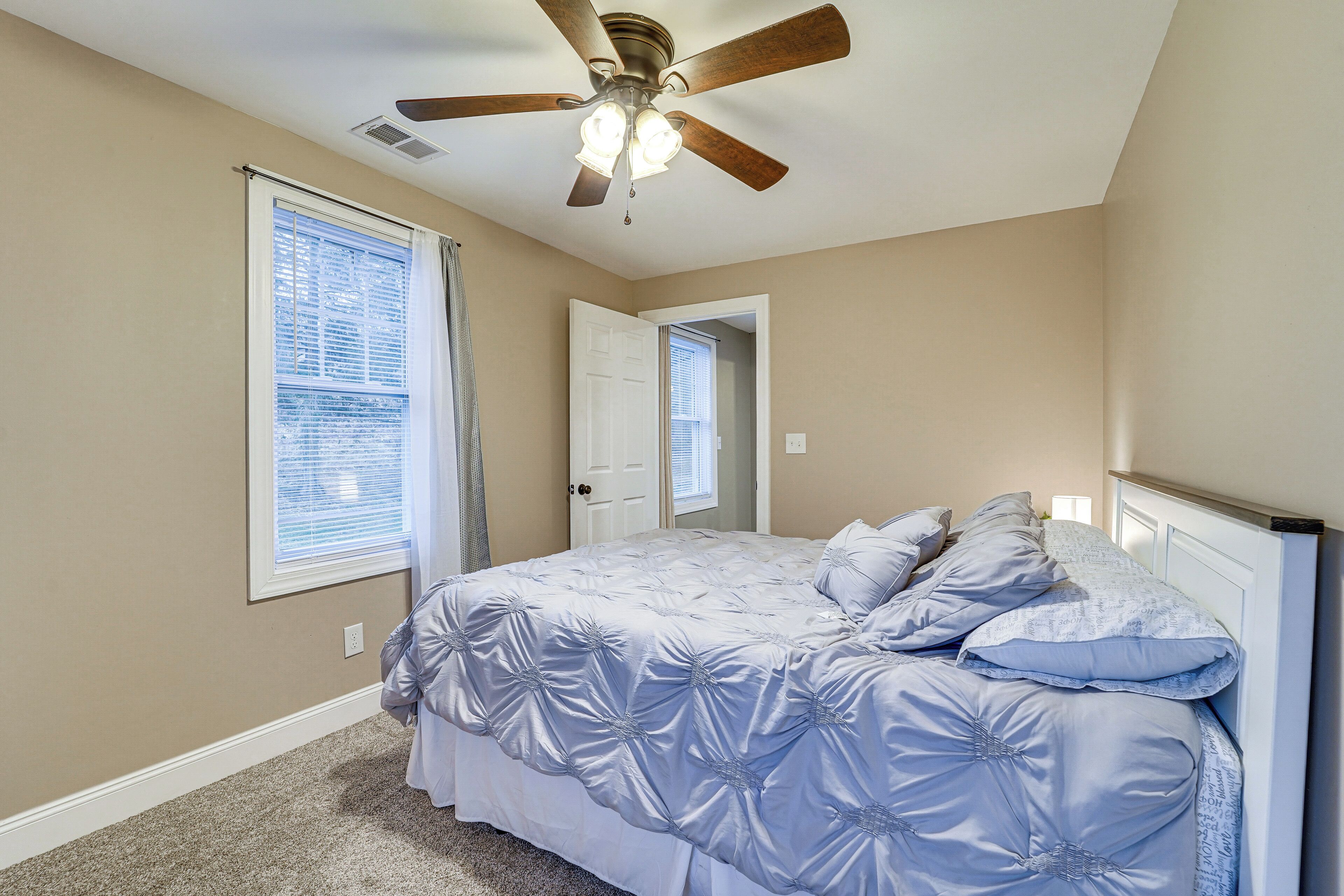 Un dormitorio con cama, ventilador de techo y puerta que da a otra habitación.