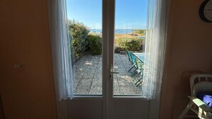 Una porta che si apre su un patio, una piscina e una spiaggia sullo sfondo.
