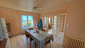 Zona pranzo con tavolo imbandito per quattro, frigorifero e vista sull'esterno.