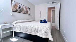 A bedroom with a bed, a desk, a chair, a wardrobe, and a door leading to another room. - Dunas Beach II - Sunset Side (Torrox)