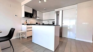 A modern kitchen with white cabinetry, a central island, and a black chair. - Dunas Beach II - Sunset Side (Torrox)