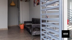 A modern living room with a grey sofa, a potted plant, and a decorative wall hanging. - Lobo studio apartments (Serrekunda)