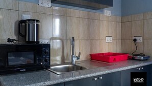 A kitchen with a microwave, sink, and red tray. - Lobo studio apartments (Serrekunda)
