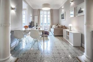 Ein modernes Wohnzimmer mit einer Couch, einem Couchtisch und einem Essbereich mit Stühlen und einem Tisch.