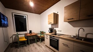 Eine kleine Küche mit Holzausstattung, einem Esstisch und einem eingebauten Backofen.