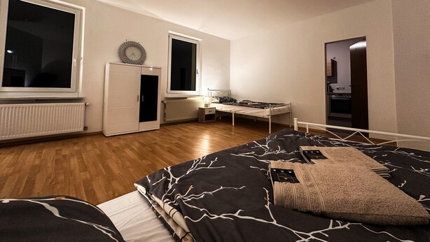 Ein Schlafzimmer mit einem Bett, einem Schreibtisch, einem Kleiderschrank und einer Heizung.