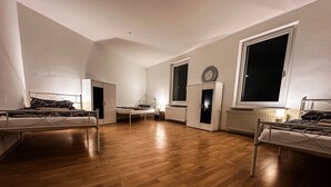 Ein Zimmer mit zwei Betten, einem Schrank, einer Heizung und einem großen Fenster.