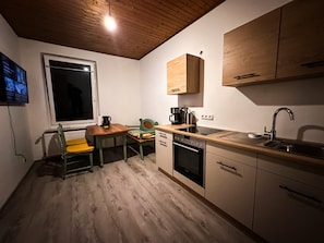 Une cuisine compacte avec des meubles en bois, un four encastré, un évier et une fenêtre.