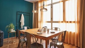 Un comedor con una mesa y sillas de madera, una planta en maceta y una ventana con cortinas.