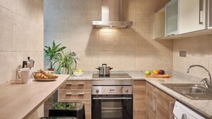 Una cocina moderna con horno empotrado, campana extractora de acero inoxidable y encimera con lavabo y frutero.