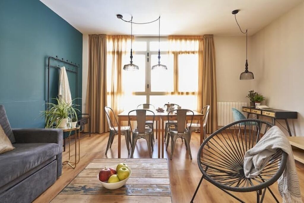 Un salon moderne comprenant un canapé, une table à manger, des chaises et une table basse sur laquelle sont disposés des fruits.