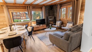 A cozy living room with a fireplace, a TV, and a dining area with a table set for four.