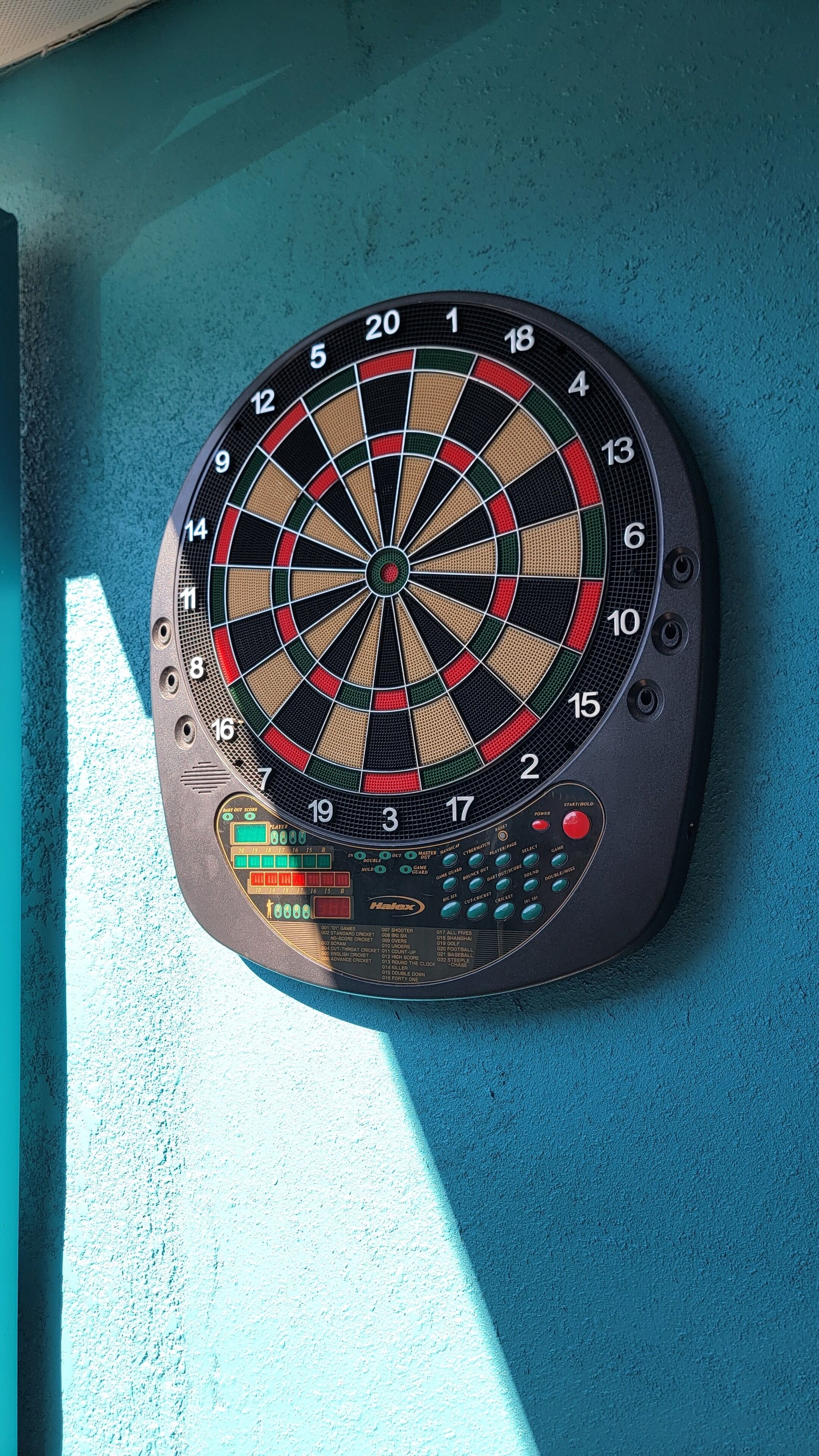 A dartboard mounted on a teal wall.