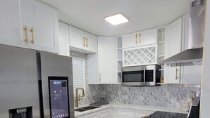 Una cocina moderna con armarios blancos, electrodomésticos de acero inoxidable y una salpicadera de mármol.