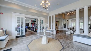 Un salon spacieux agrémenté d’un grand lustre, d’une table basse ronde et d’un coin salon avec des canapés et un tapis.