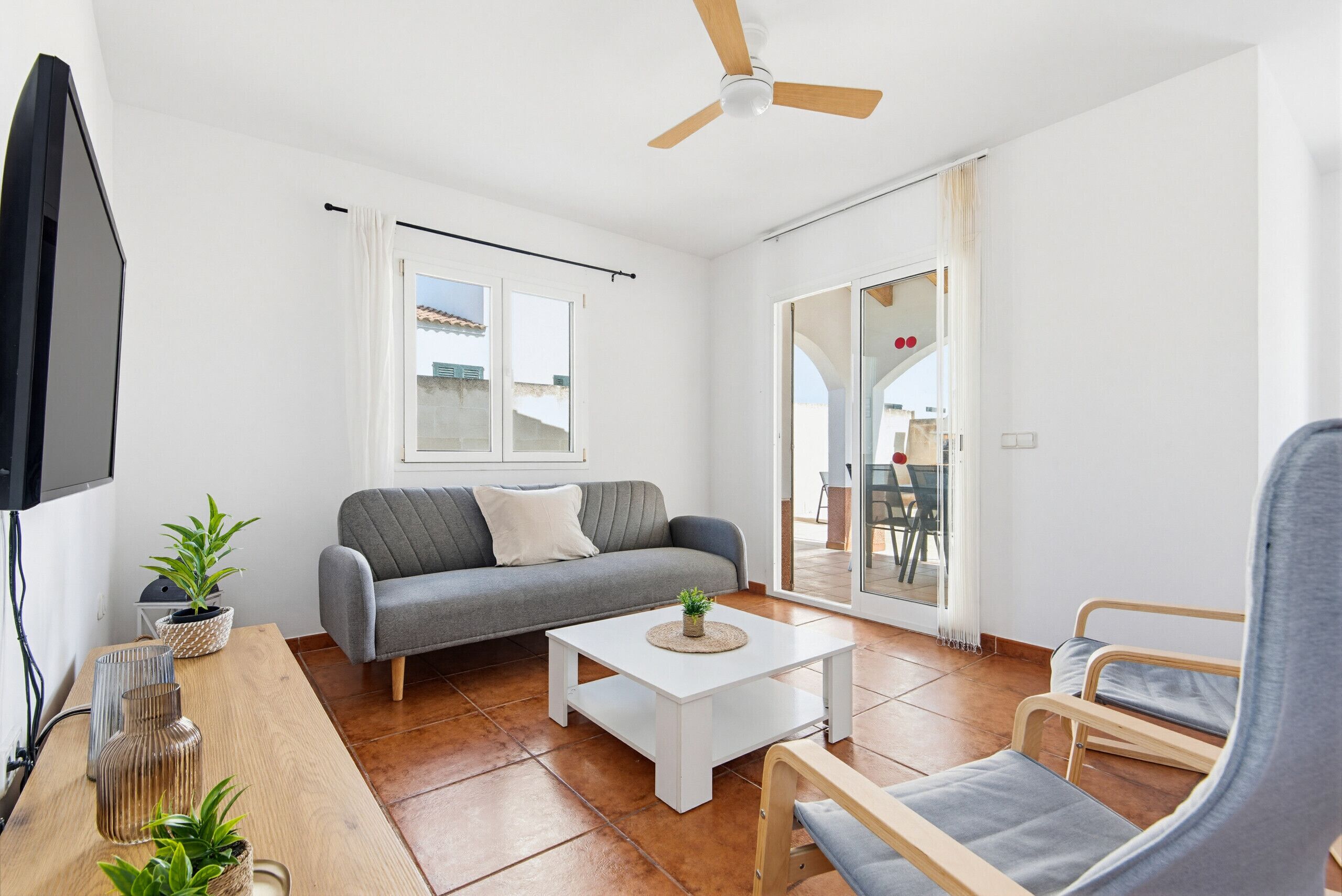 A living room with a sofa, a coffee table, a TV, and a ceiling fan.
