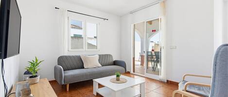 A living room with a sofa, a coffee table, a TV, and a ceiling fan.