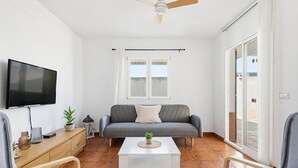 En stue med sofa, sofabord, fjernsyn og loftventilator.