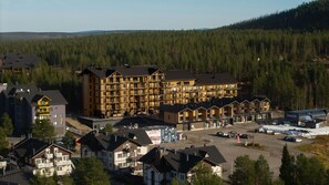 A multi-story hotel with a central courtyard, surrounded by forested hills.