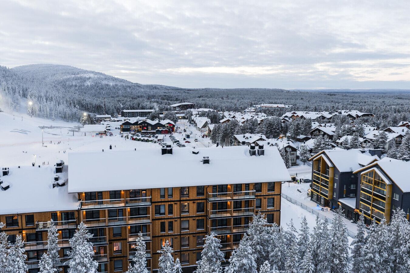 Une station de ski enneigée, dotée de bâtiments modernes, de pistes de ski et entourée de montagnes.