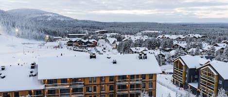 Une station de ski enneigée, dotée de bâtiments modernes, de pistes de ski et entourée de montagnes.