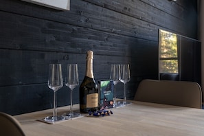 A wooden table with a bottle of Bolla Prosecco wine, four wine glasses, and a welcome card.