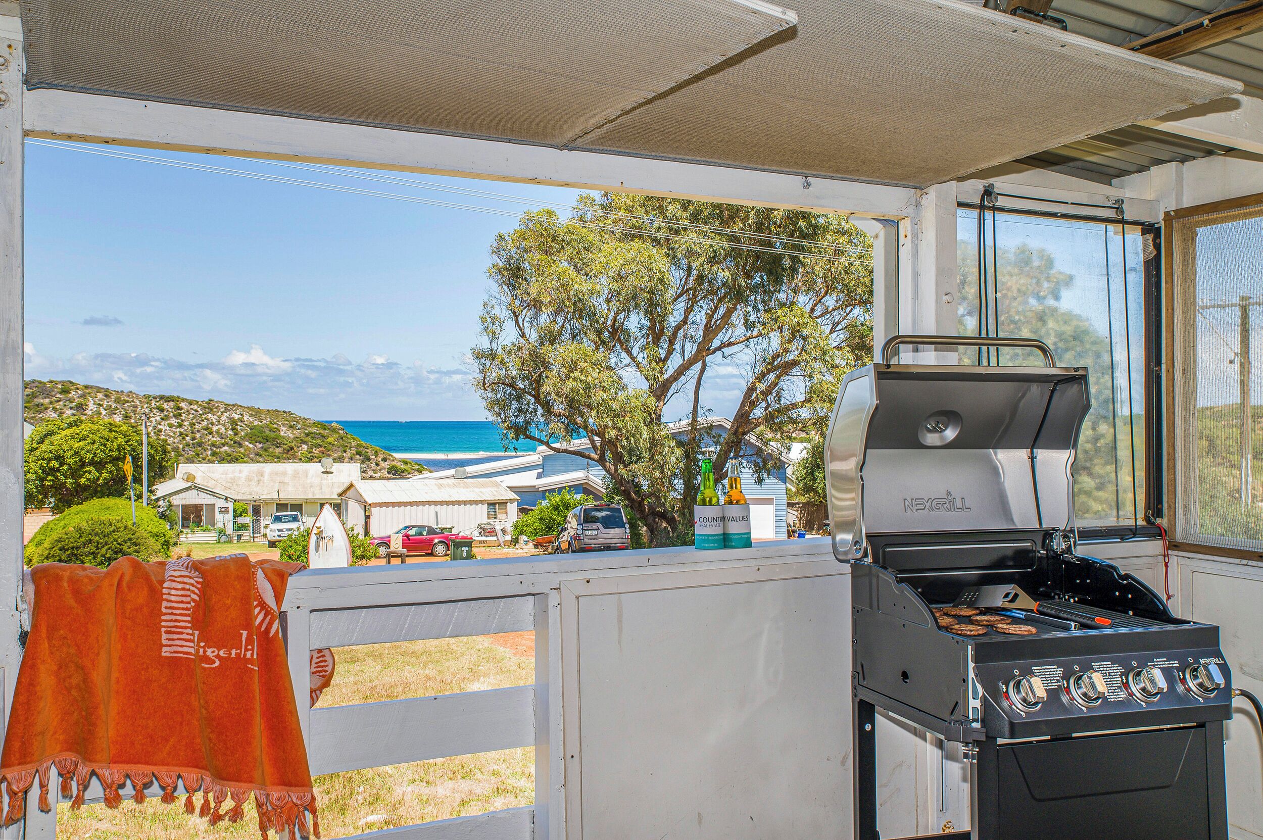 A barbecue grill with a view of the sea and houses in the background.