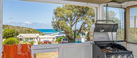 A barbecue grill with a view of the sea and houses in the background.