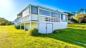 A single-story mobile home with a covered porch, a garage, and a well-maintained lawn.