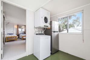A compact kitchen with a washing machine, refrigerator, and a window with a view of trees. - Love You Moore-Breathtaking Views of Both Ocean and River. (Guilderton)