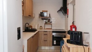 Eine kleine Küche mit einem weißen Kühlschrank, Holzschränken, einer Mikrowelle und einem Geschirrspüler.