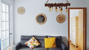 Ein modernes Wohnzimmer mit einem grauen Ecksofa, einem Holzesstisch und einer Pendelleuchte.
