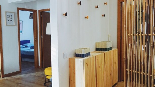 Ein modernes Interieur mit einer hölzernen Bank, einer Pendelleuchte und einem an der Wand befestigten Korbträger.
