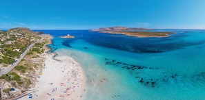 An aerial view of a coastal area with a beach, clear blue waters, and a road leading to a settlement. - Charming Sea Villas-villa Sleeps 6IN Shared Pool (Stintino)