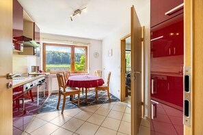 A kitchen with a dining table, chairs, and a window with a view of greenery. - Apartment "Haus Wacholderheide" with Private Terrace, Garden and Wi-Fi (Albstadt)