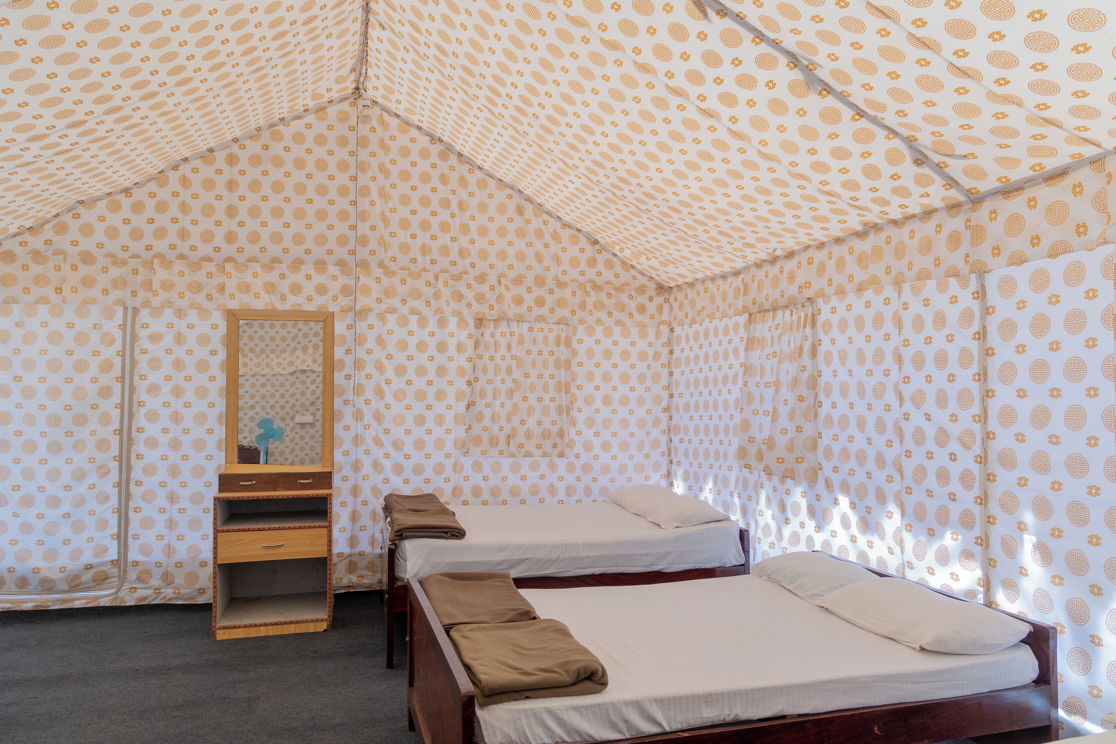 Una habitación con dos camas, un aparador de madera y un espejo.