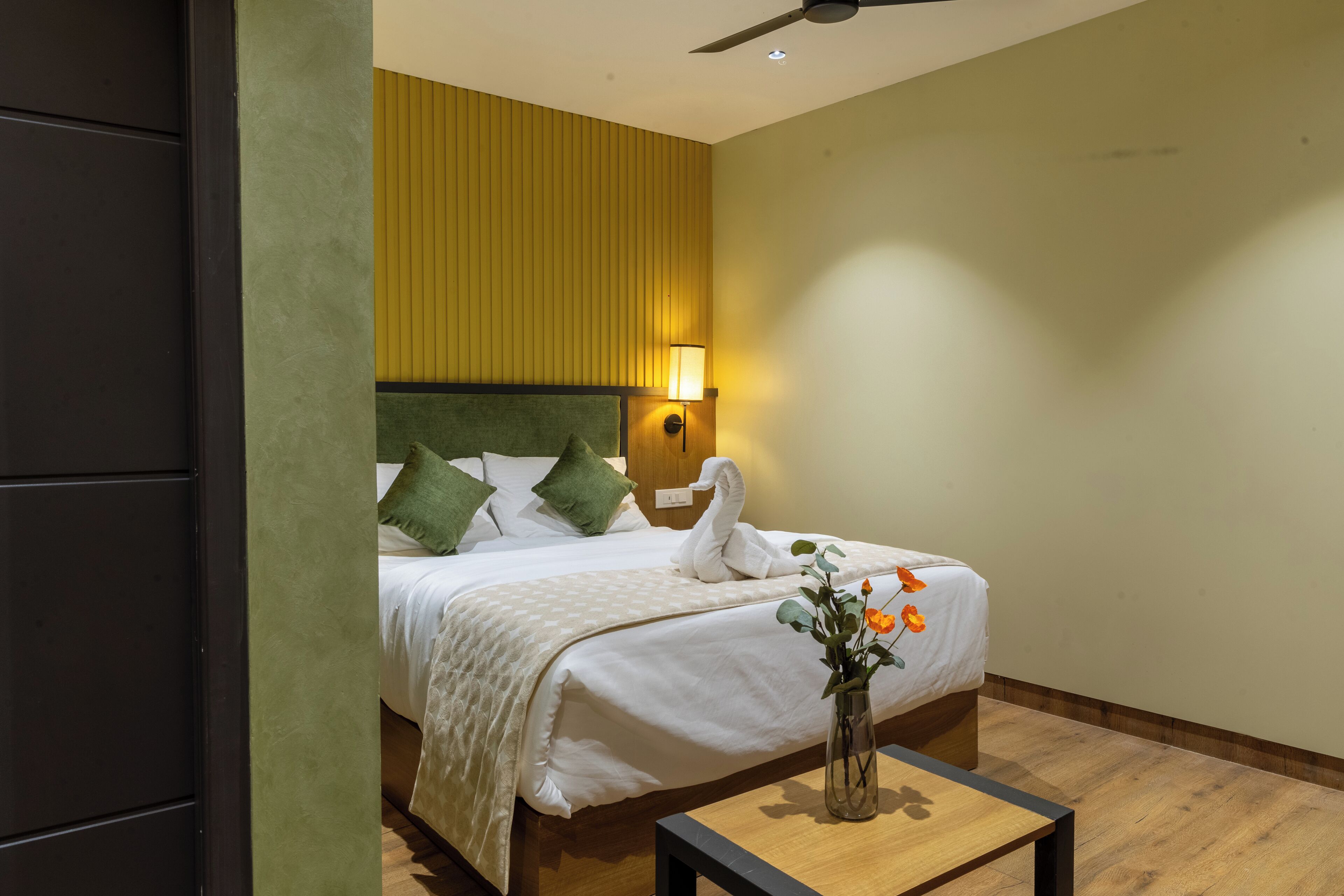 A hotel room with a bed, a nightstand, a lamp, and a vase with flowers.