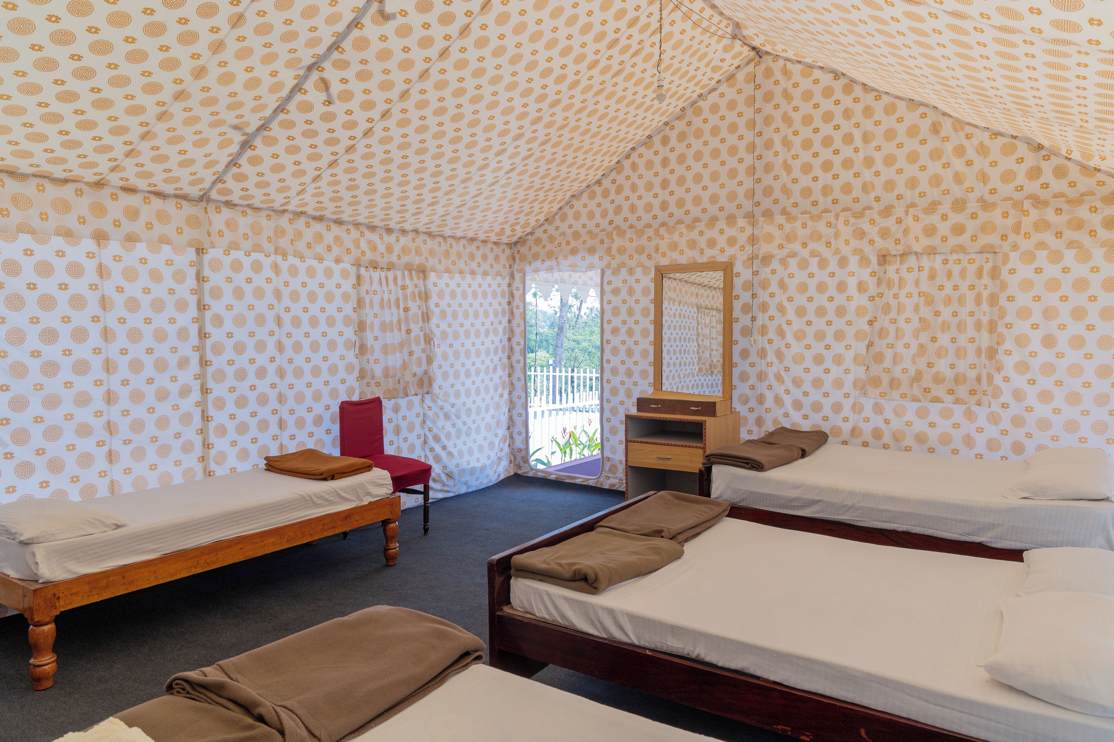 A room with two wooden beds, a red chair, a mirror, and a small desk.