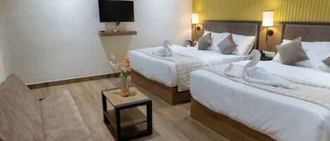 Une chambre d’hôtel avec deux lits, une télévision, une petite table avec un vase et une chaise.