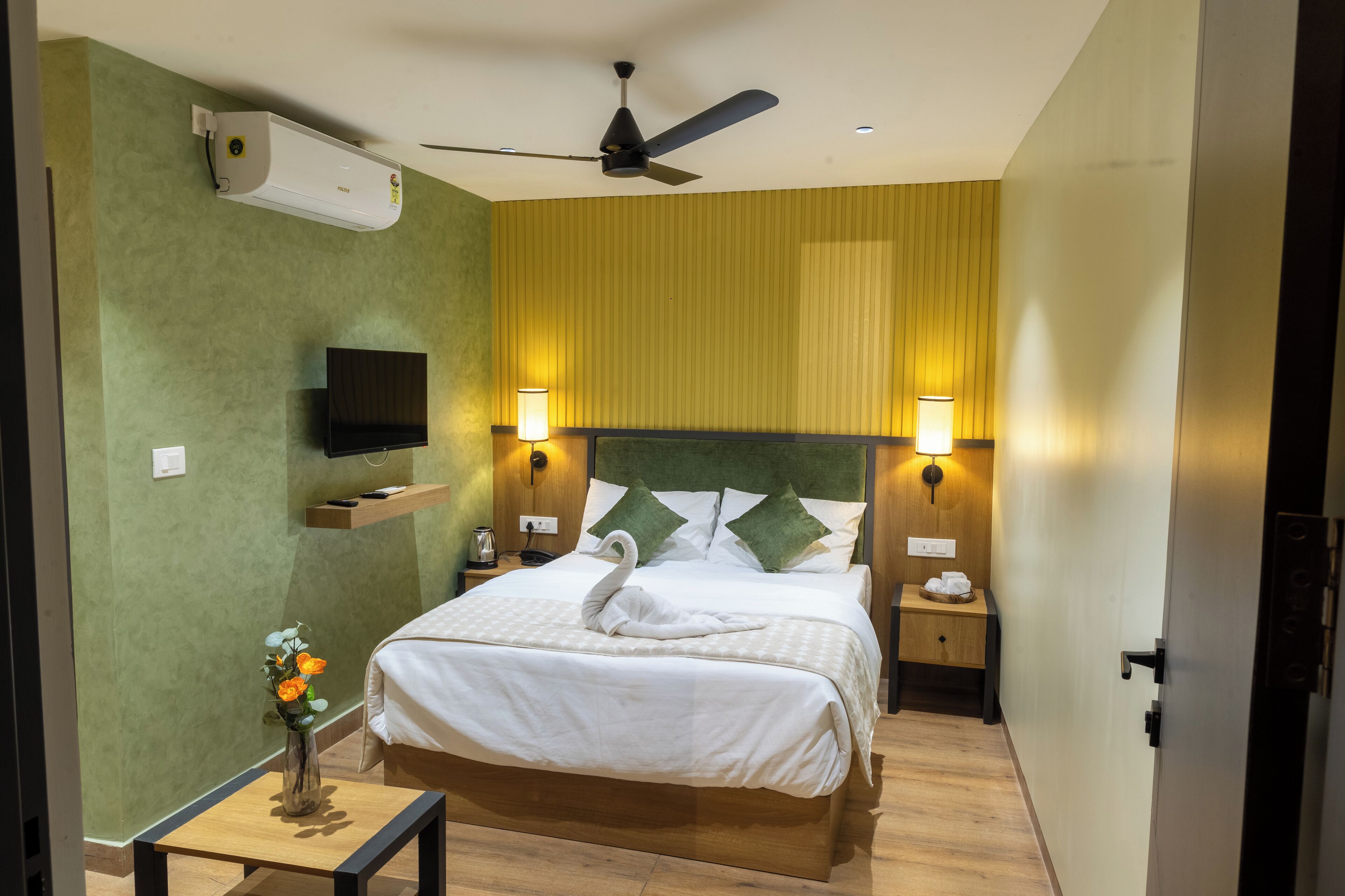 Une chambre d’hôtel équipée d’un lit, de lampes de chevet, d’un téléviseur à écran plat, d’un ventilateur de plafond et d’un appareil de climatisation.